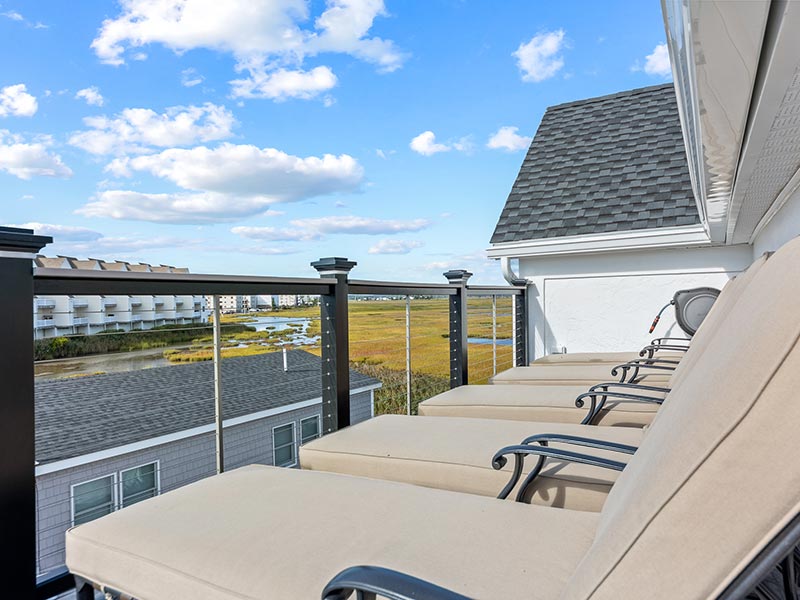 Balcony with beach chairs and a view of a neighborhood by the beach